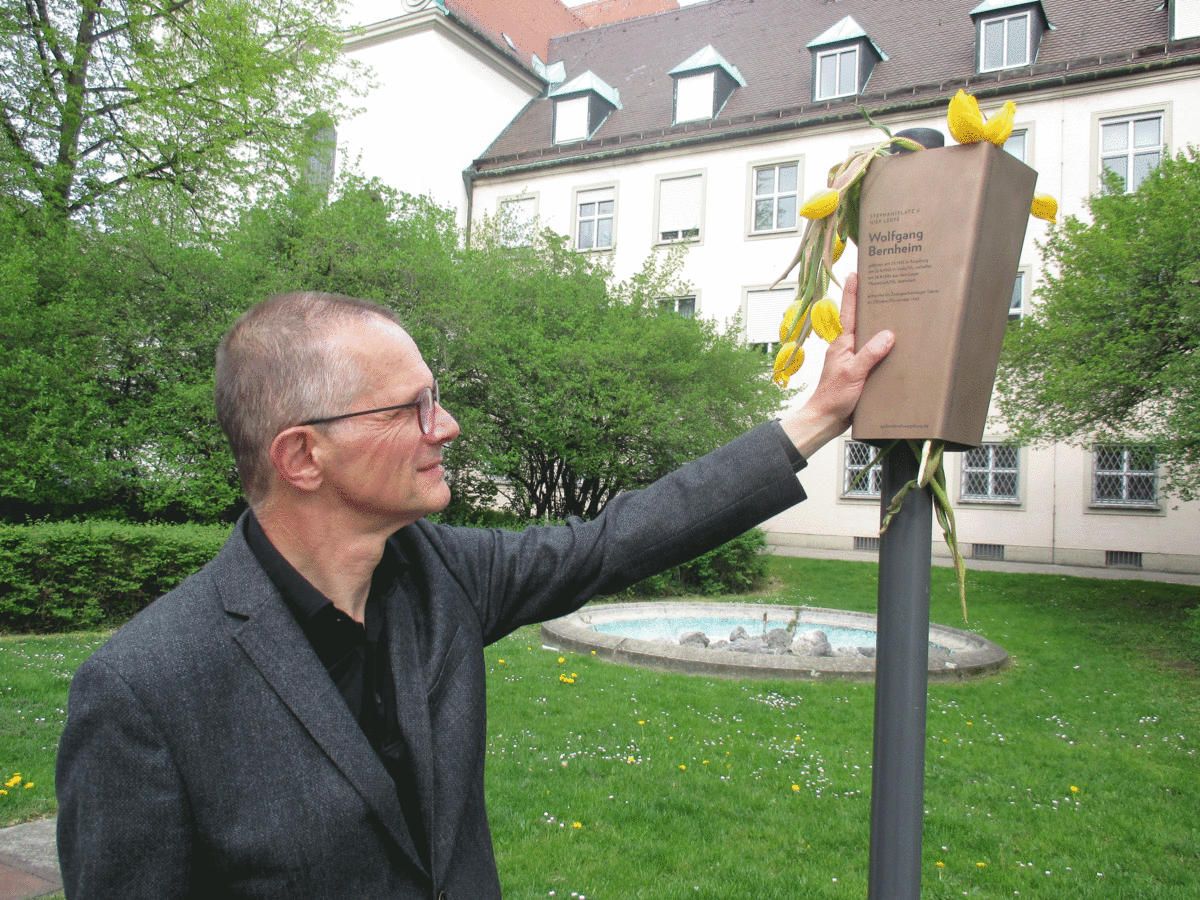 Michael Bernheim hat das Erinnerungsband, auf dem die Lebensdaten seines Onkels festgehalten sind, des Märtyrers Frater Paulus, mit Tulpen geschmückt. Im Mai vor einem Jahr ist es auf dem Augsburger Stephansplatz aufgestellt worden.  Foto: Buck