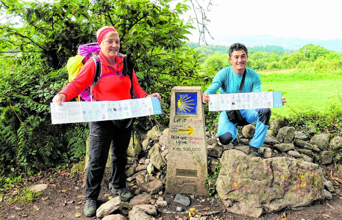 Isabel Braña und ihr Begleiter Miguel Díaz zeigen am 100-Kilometer-Stein vor Santiago ihre gestempelten Pilgerausweise. (Foto: Drouve)