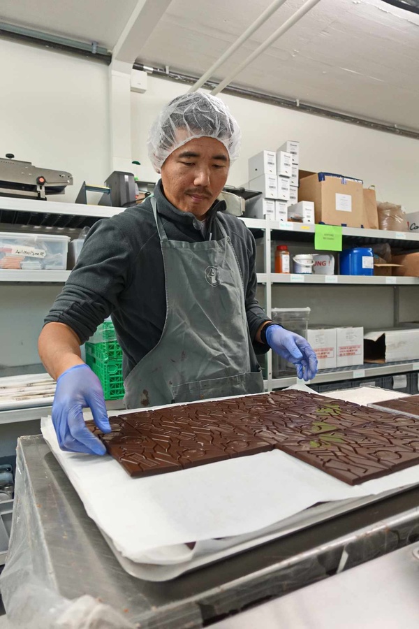 Ein Mitarbeiter der Manufaktur, der aus Tibet stammt, sortiert Schokoladentafeln. (Foto: Wiegand)