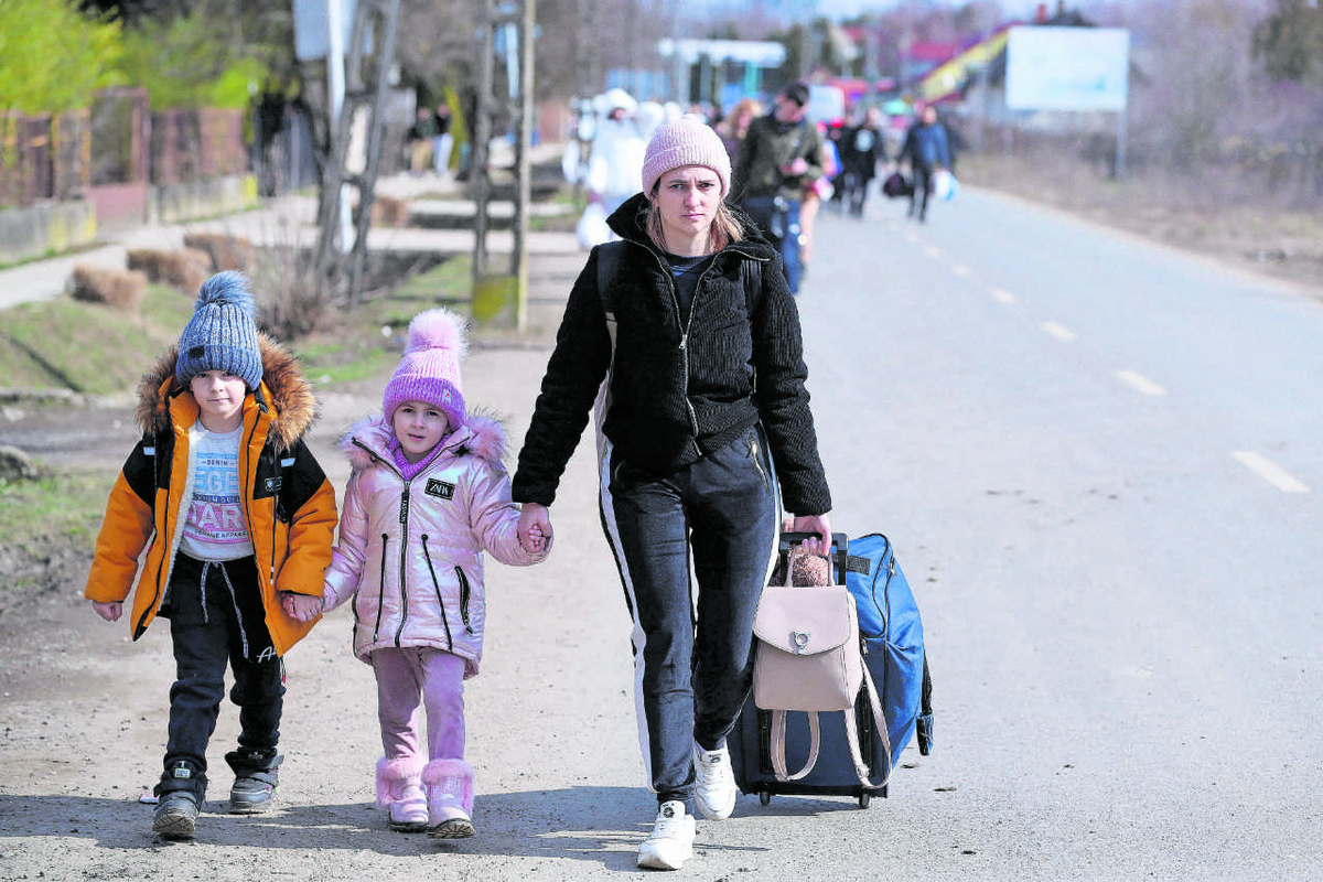 Eine ukrainische Mutter erreicht mit zwei kleinen Kindern den Grenz­übergang Tisza­becs. Die ungarischen Behörden haben die Kontrollstelle aufgehoben und versorgen die Kriegsflüchtlinge mit Lebensmitteln und Kleidung. (Foto: Imago/Pixsell)