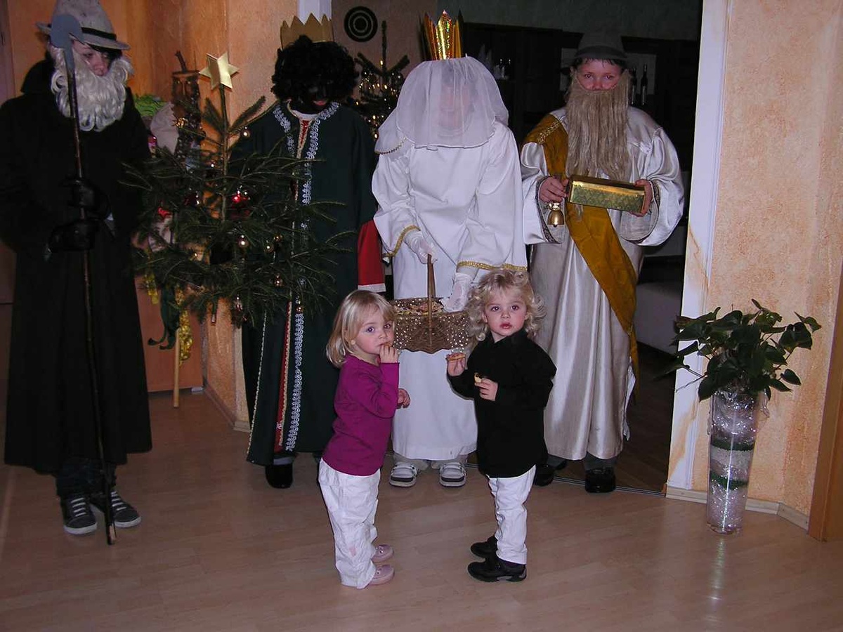Zwei kleine Kinder nehmen sich Plätzchen aus dem Korb des Christkinds, das sein Gesicht mit einem weißen Schleier verhüllt. (Foto: Kleinhenz)