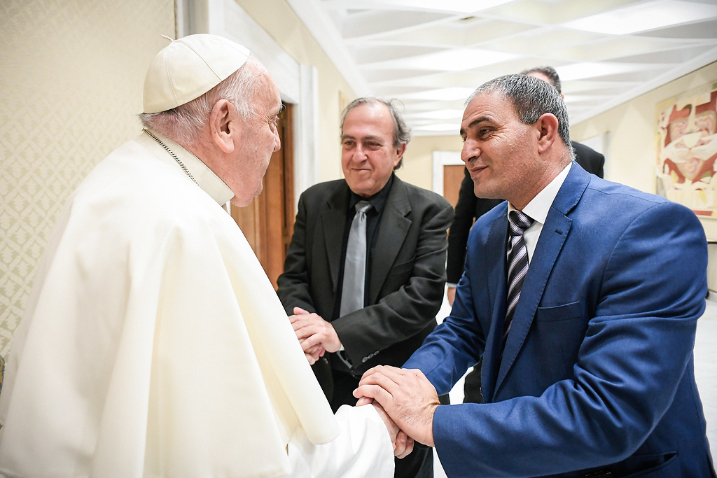Papst Franziskus begrüßt den Israeli Rami Elhanan (m.) und den Palästinenser Bassam Aramin (r.), Väter von zwei im Nahostkonflikt getöteten Mädchen; am 27. März 2024 vor der Generalaudienz im Vatikan. (Foto: KNA)