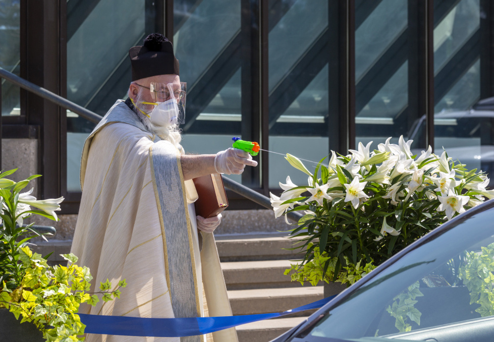 Der Priester Timothy Pelc segnet Osterkörbe mit Blumen mit Weihwasser mit Hilfe einer Wasserpistole zum Schutz vor Ansteckung mit dem Coronavirus am Samstag, den 11. April 2020 in Grosse Pointe Park (USA). (Foto: KNA)