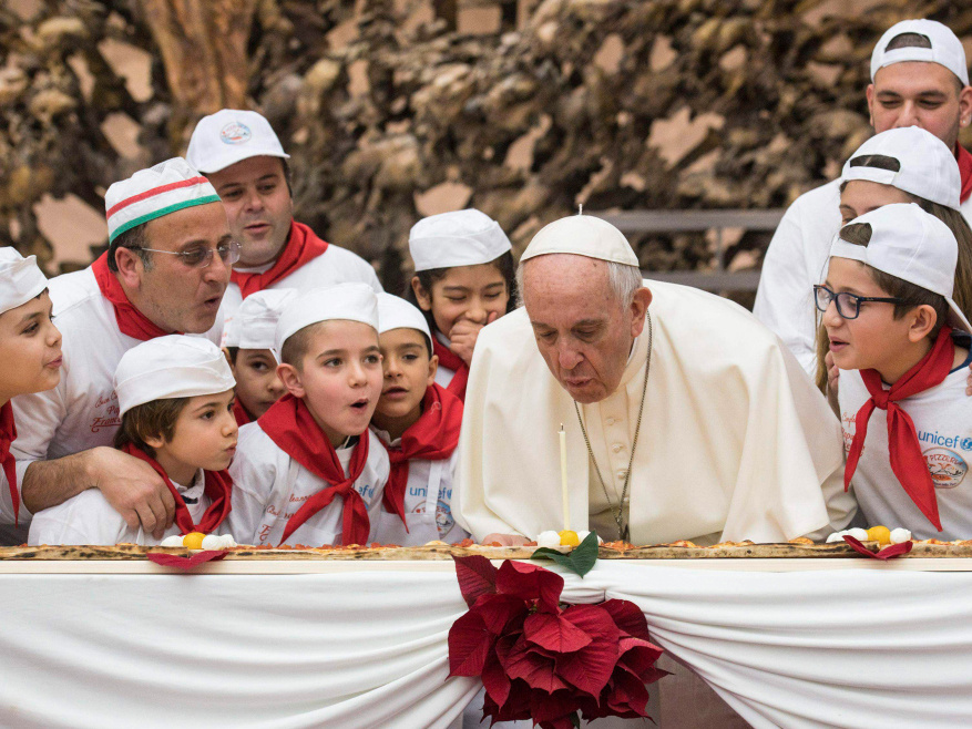 Kinder pusten mit Papst Franziskus zu seinem 81. Geburtstag am 17. Dezember 2017 im Vatikan eine Kerze auf seiner Geburtstagspizza aus. (Foto: KNA)