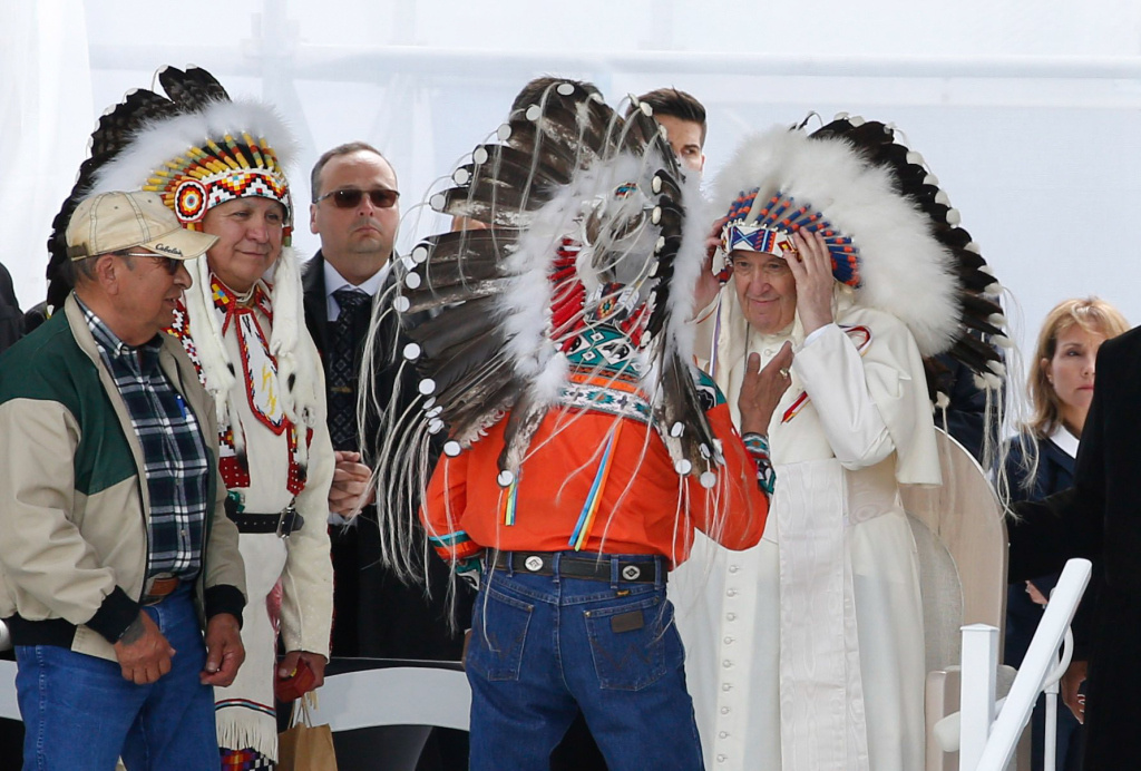 Papst Franziskus rückt ein Warbonnet auf seinem Kopf zurecht, einen traditionellen indigenen Kopfschmuck mit Federn, während der Begegnung mit den indigenen Gruppen First Nations, Metis und Inuit am 25. Juli 2022 in Maskwacis (Kanada). (Foto: KNA)