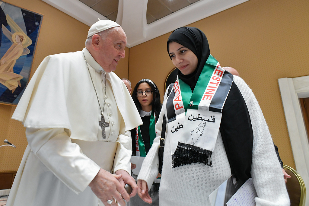 Papst Franziskus spricht mit einer jungen Frau mit Kopftuch und einem Schal in den Farben der palästinensischen Fahne um die Schultern, bei seinem Treffen mit Angehörigen von Palästinensern in Gaza am 22. November 2023 im Vatikan. (Foto: KNA)