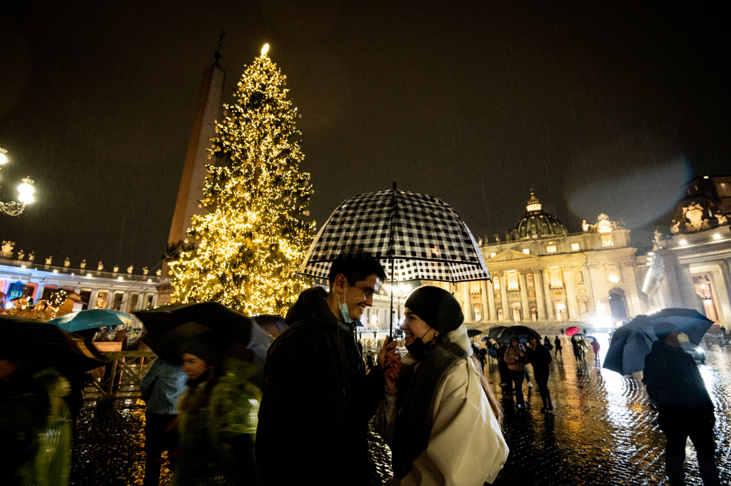 Ein Paar unter einem Regenschirm vor dem geschmückten Christbaum auf dem illuminierten Petersplatz im Vatikan am 10. Dezember 2021. (Foto: KNA)