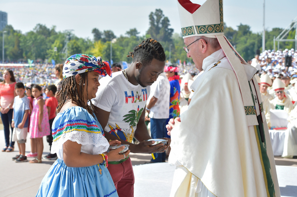 Ein Mann und eine Frau in bunter Kleidung bringen Papst Franziskus Gaben während des Gottesdienstes im O'Higgins-Park in Santiago de Chile. (Foto: KNA)